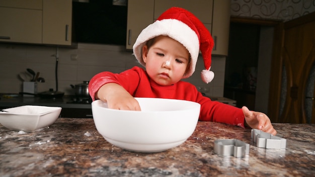 新年の夕食を準備するサンタの帽子をかぶった子供