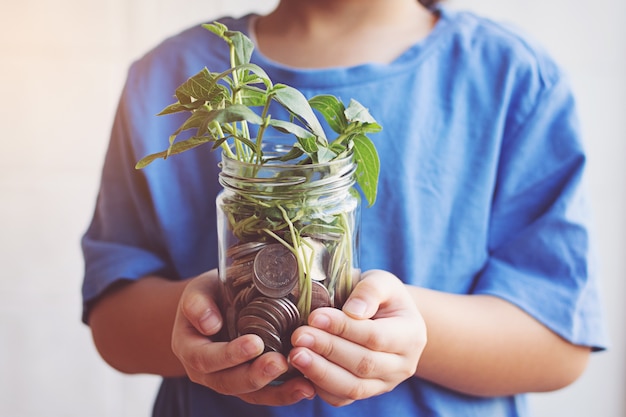 Photo child saving money in bottle money growing up as tree