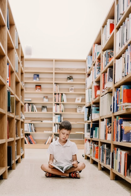 学校図書館の子供。子供たちは本を読みます。小さな男の子が読んで勉強しています。書店の子供たち。借りる本を選ぶ賢いインテリジェントな就学前の子供。