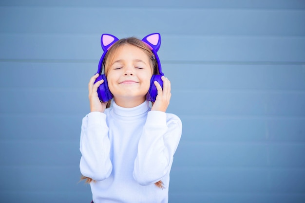 A child, a schoolboy, listens to music in wireless bright headphones. Modern Bluetooth headphones