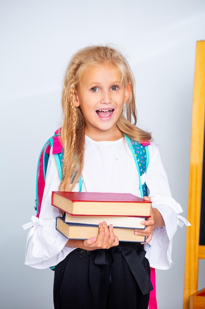 Bambina studentessa felice e bella su uno sfondo bianco torna a scuola