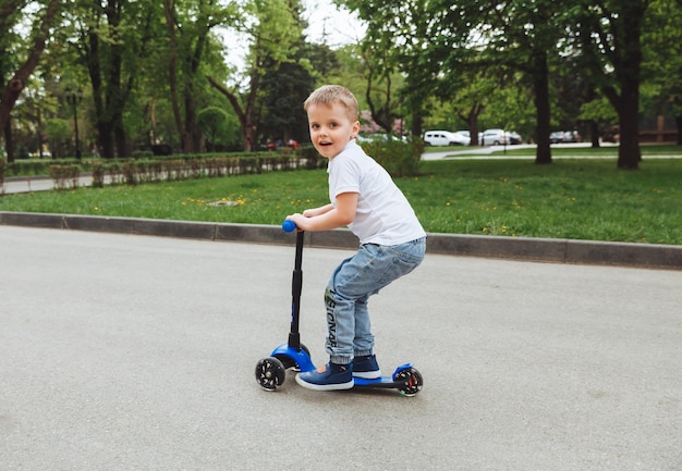 公園でスクーターに乗っている子供晴れた日に小さな男の子がスクーターに乗る未就学児のためのアクティブなスポーツ