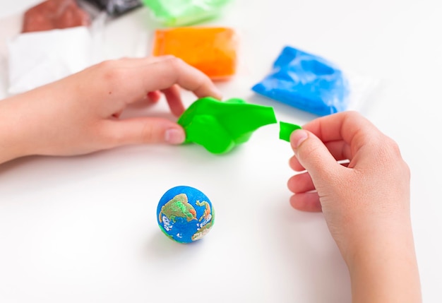 어린이가 공기 플라스틱으로 지구본을 조각합니다.