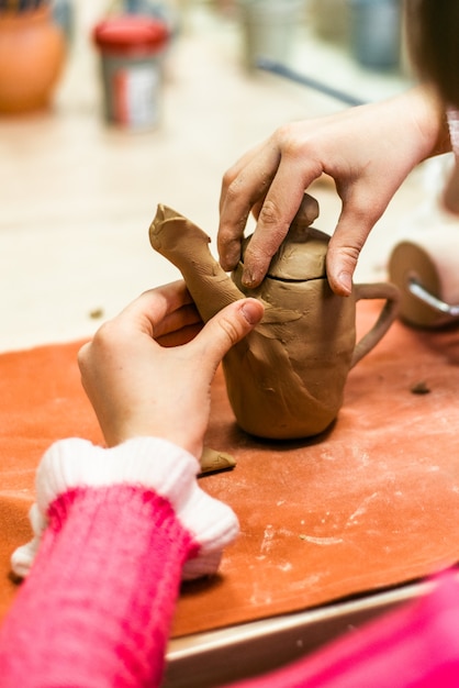 子供は生の粘土から製品を彫刻します