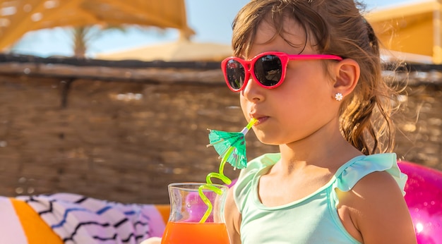 A child at the sea drinks a cocktail. 