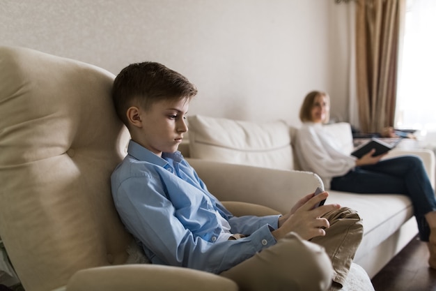 Child sits in a chair looks at the phone