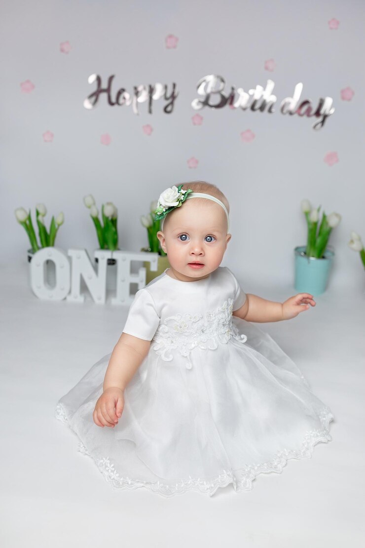 a child sits in front of flowers and the word one on a white background girl in a white dress