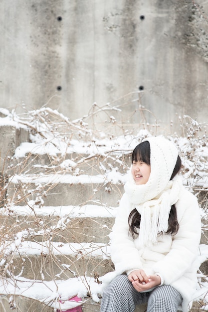 The child sits on the stairs and smiles at the snow