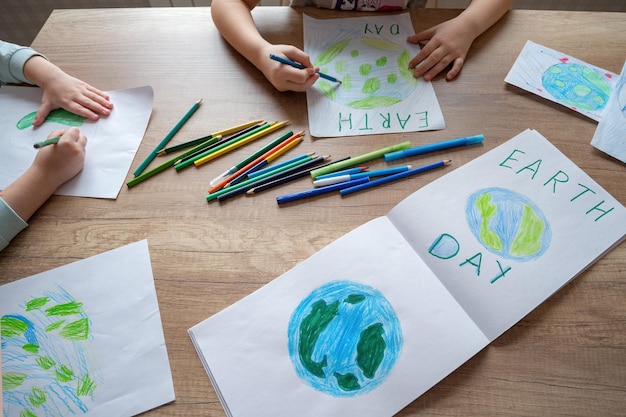 A child sits at a table with a drawing of the earth and the words earth day.