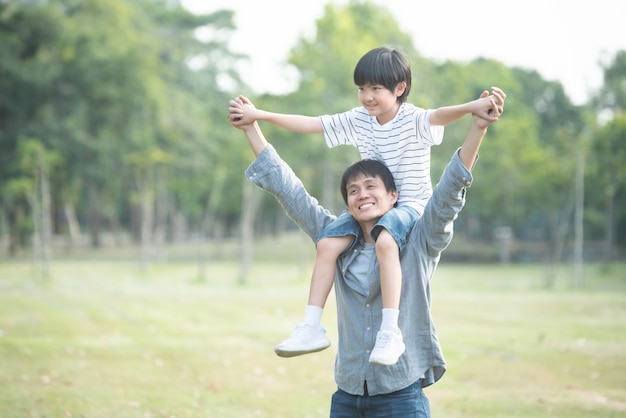 ребенок сидит на плечах отца в общественном парке