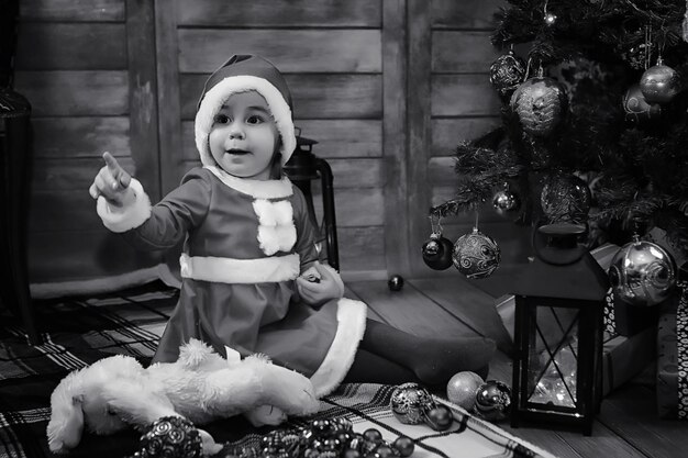 サンタクロースを待っているクリスマスツリーの前に座っている子供