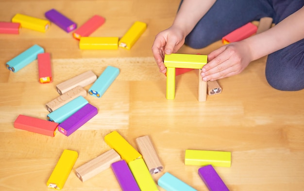 Foto bambino seduto a terra nell'appartamento e che gioca con blocchi giocattolo colorati gioco educativo