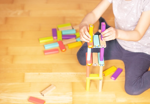 Foto bambino seduto per terra nell'appartamento e che gioca con blocchi giocattolo colorati