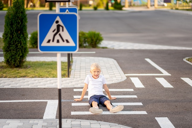 Child sitting on the road at a pedestrian crossing