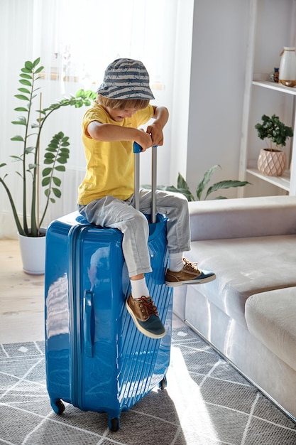 A child sitting on a suitcase have fun and laughs waiting for a trip on vacation