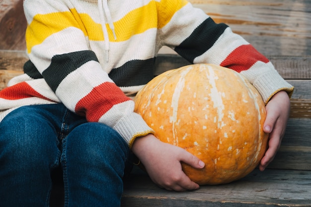 Child sitting with pumpkin in his hands