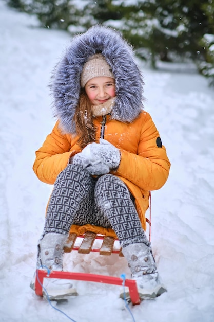 写真 子供そりはそりに座って雪を投げる