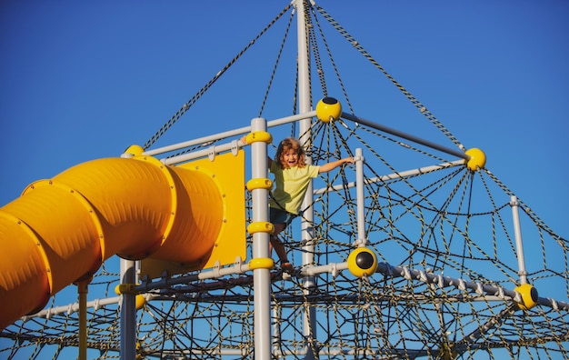 Child on slide playground area kid boy climbed on top of the\
rope web kids growth concept