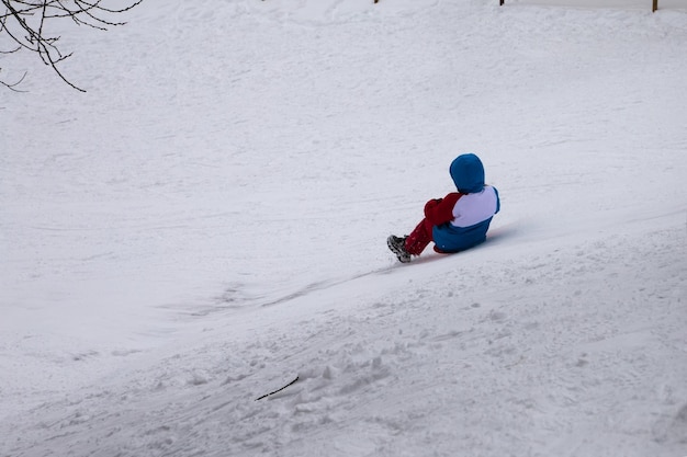 子供は雪の滑り台を滑り降ります。