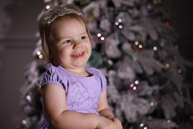 Child in smart clothes in front of the Christmas tree Waiting for the new year