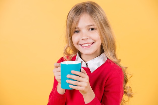 Child smile with blue cup on orange background