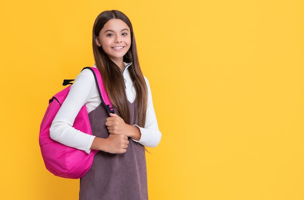 Child smile with school backpack on yellow background