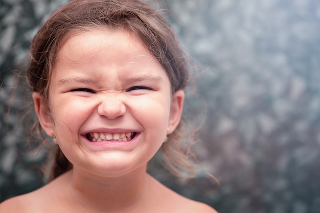 Child smiles showing teeth. Girl brushing her teeth in the bathroom