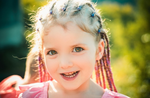 Photo child smiling girl with hairstyle dreadlocks kid with fashionable hair on blur background outdoor