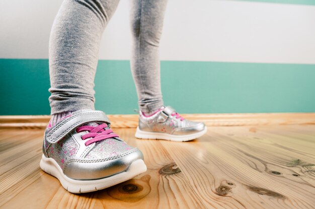 Child in sneakers on wooden surface