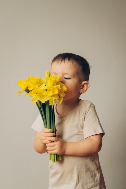 한 아이가 노란 수선화 꽃다발 냄새를 맡는다