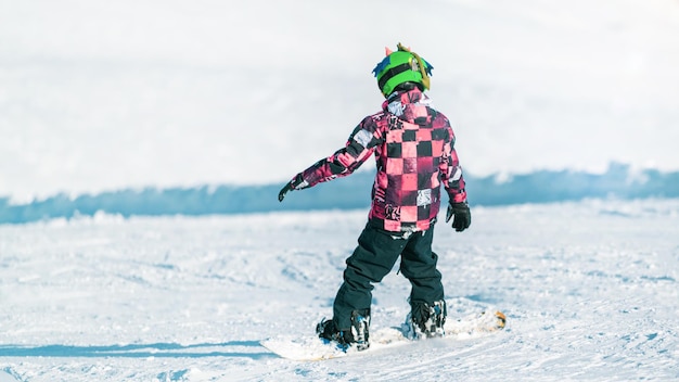 子供が山でスノーボードをしている
