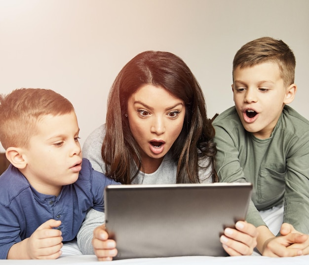 Child son mother family surprised shocked amazed playing kid childhood tablet bed technology