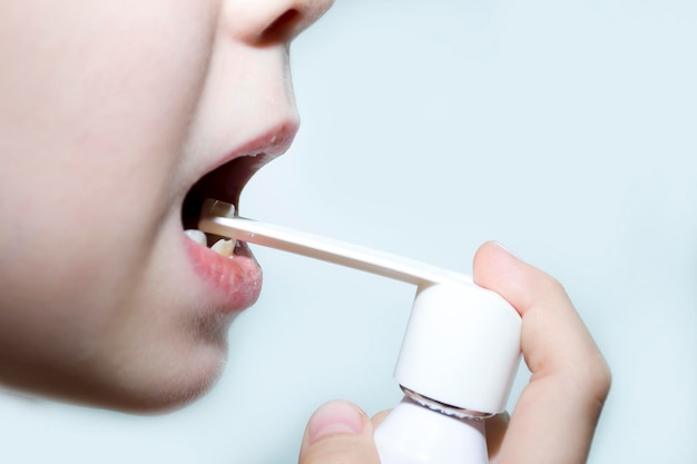 Foto il bambino spruzza la medicina con uno spray