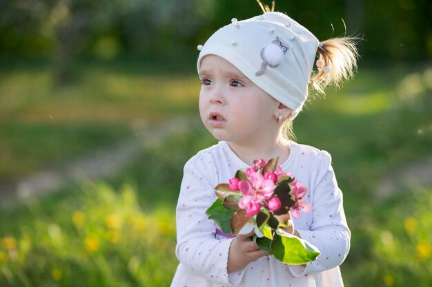 春の庭の子供 リンゴの花の花束を持っている少女