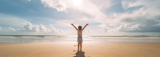 A child stands on a beach with his arms outstretched.