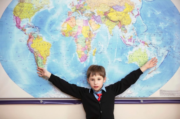 The child stands at the geographical map of the world