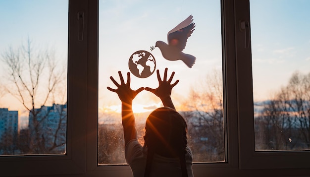 Child stretches his hands sunlight outside window flying dove world with branch forces globe concept peace world no war ecology