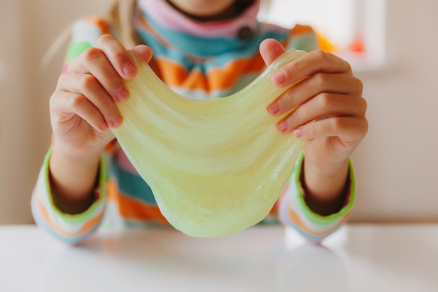 The child stretches the mucus to the sides. Children's hands are playing slime. Making slime. Copyspace. Selective focus. Layout for text.