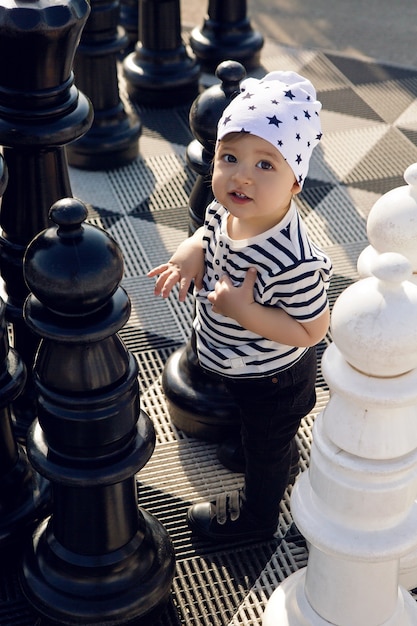 child in a striped shirt plays with large chess pieces