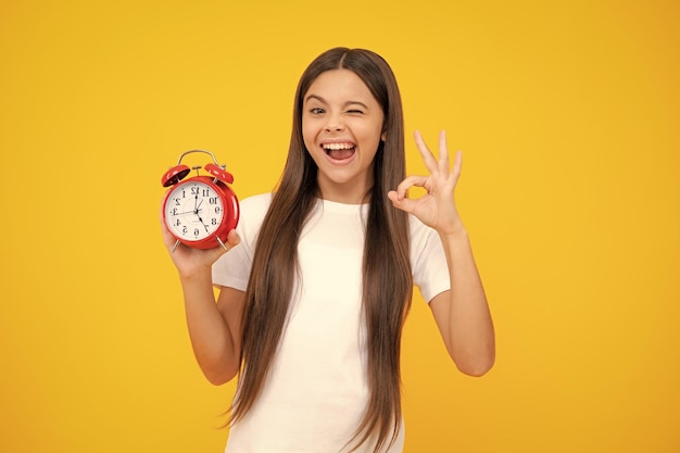 Child student girl with clock isolated on yellow background child back to school education and time