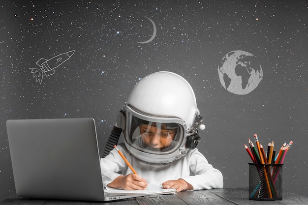 Foto il bambino studia a distanza a scuola, indossando un casco da astronauta. di nuovo a scuola