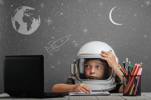 The child studies remotely at school, wearing an astronaut's helmet. back to school