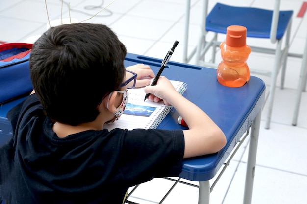 Ребенок учится в классе с книгами и тетрадями на столе