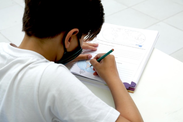 Ребенок учится в классе с книгами и тетрадями на столе