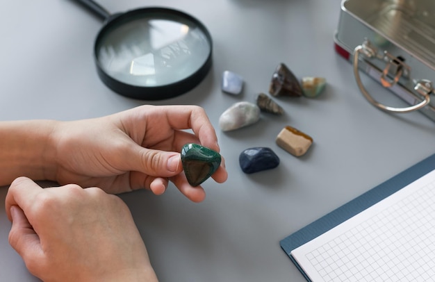 Ребенок изучает коллекцию полудрагоценных камней на сером столе с принадлежностями детская наука