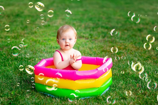 子供は夏にシャボン玉のある緑の芝生の上で膨らませてプールで泳ぐテキスト用のスペース