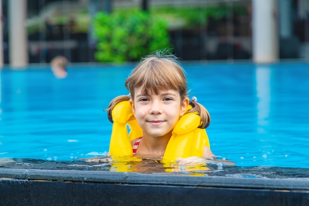 The child swims in the pool in the summer.