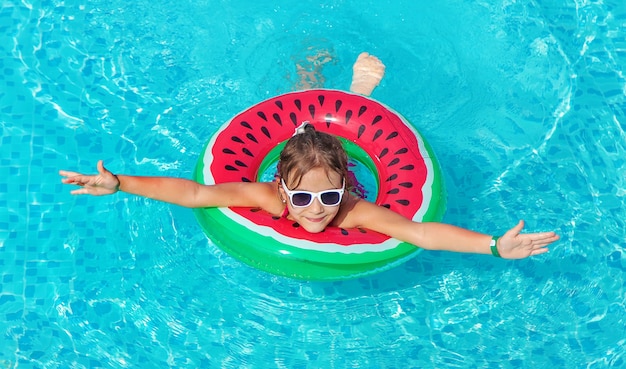 Foto il bambino nuota in piscina con un cerchio. ragazzo.