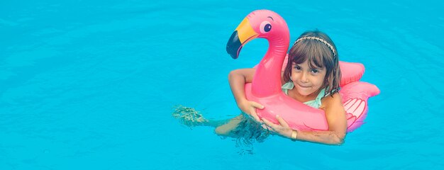 A child swims in a pool with rubber flamingo