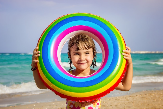 A child swims in a swimming pool with a life preserver. 